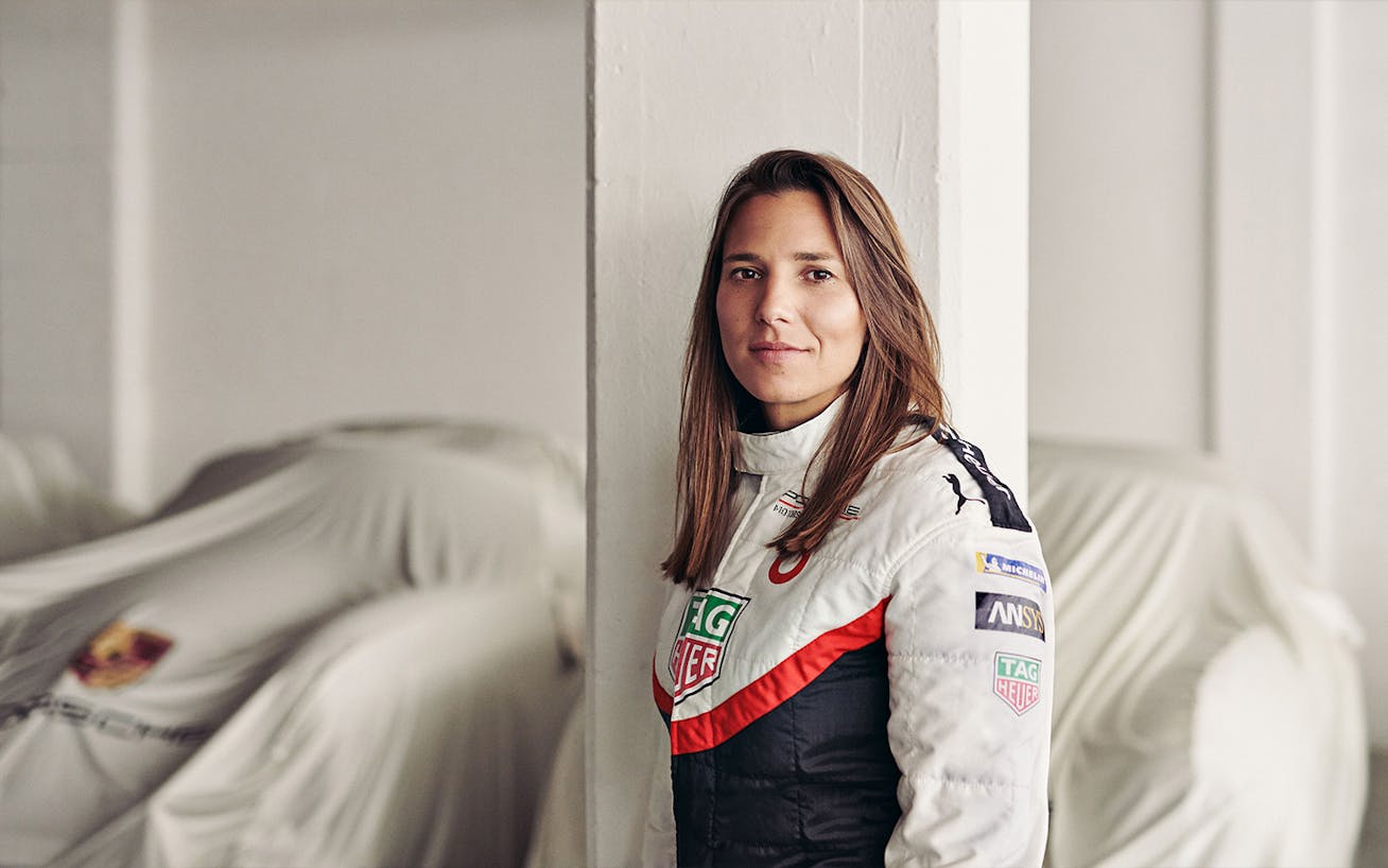 Woman with Porsche racecars, under dust sheets, in the background