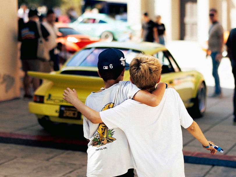 Two boys hug, looking at Porsche 911 Carrera RS 2.7