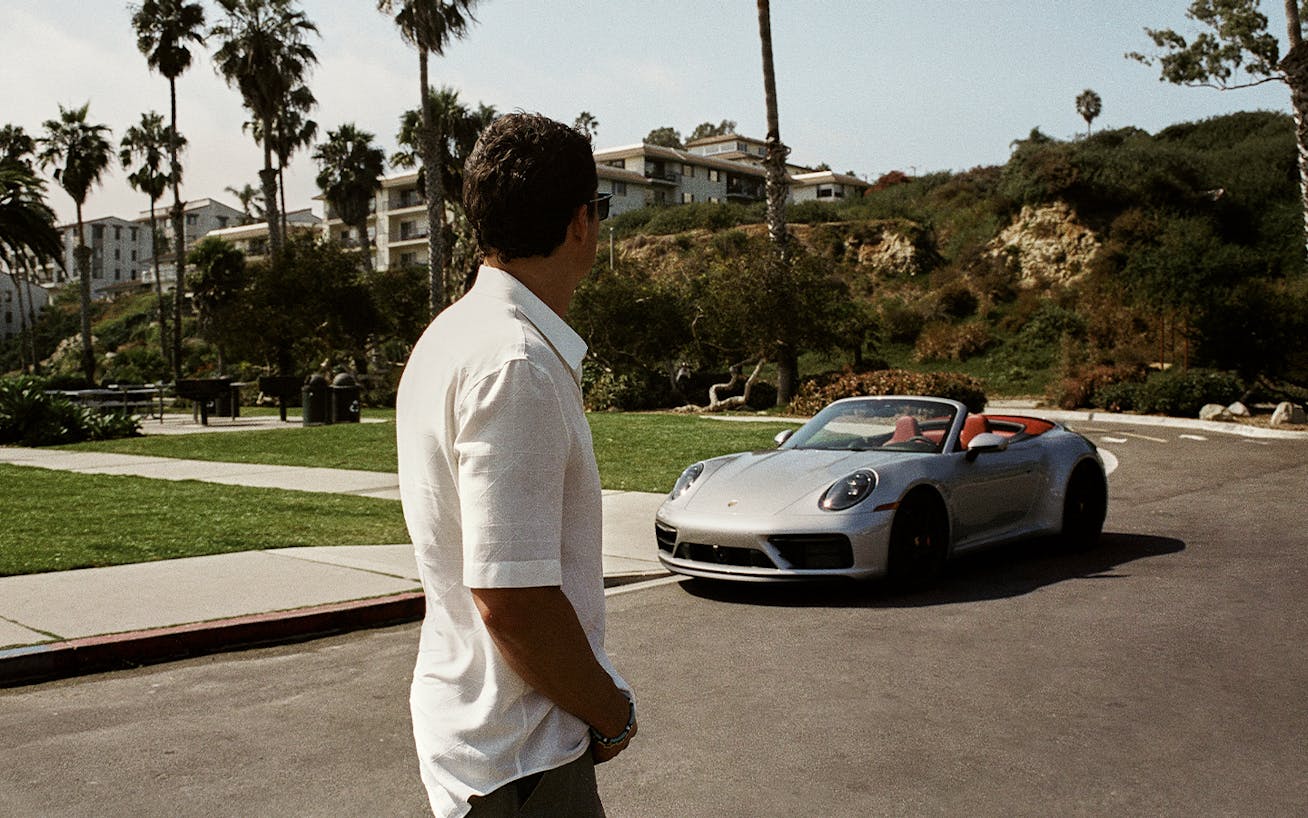 Man looking back at silver Porsche 911 Carrera GTS Cabriolet