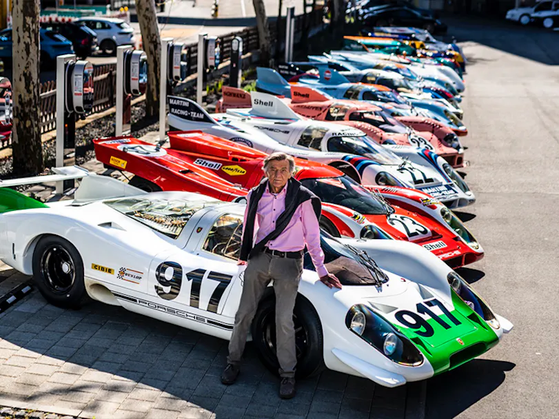 Famous German engineer Hans Mezger leaning on a Porsche 917 race car 