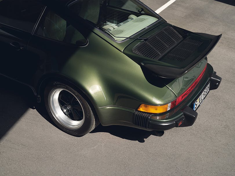 Green Porsche 911 G series in parking lot 