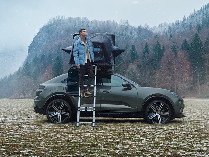 Man on ladder with grey Porsche Macan with roof tent