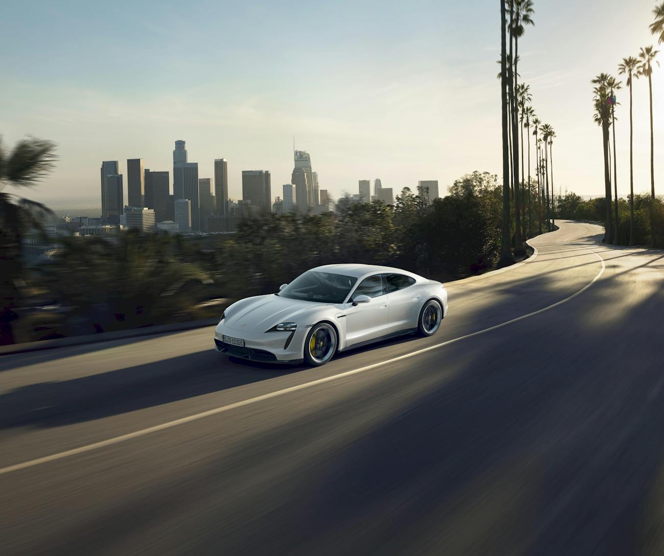 Porsche Taycan Turbo S on road, downtown Los Angeles behind