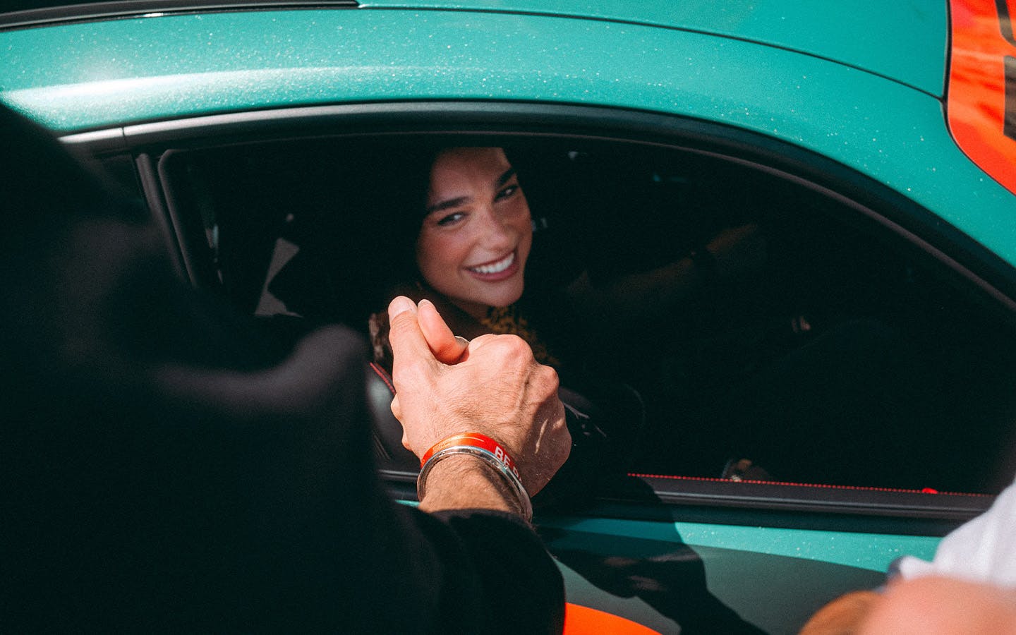 Dua Lipa shakes hand sat in Dua Lipa Rennstall GT3 RS