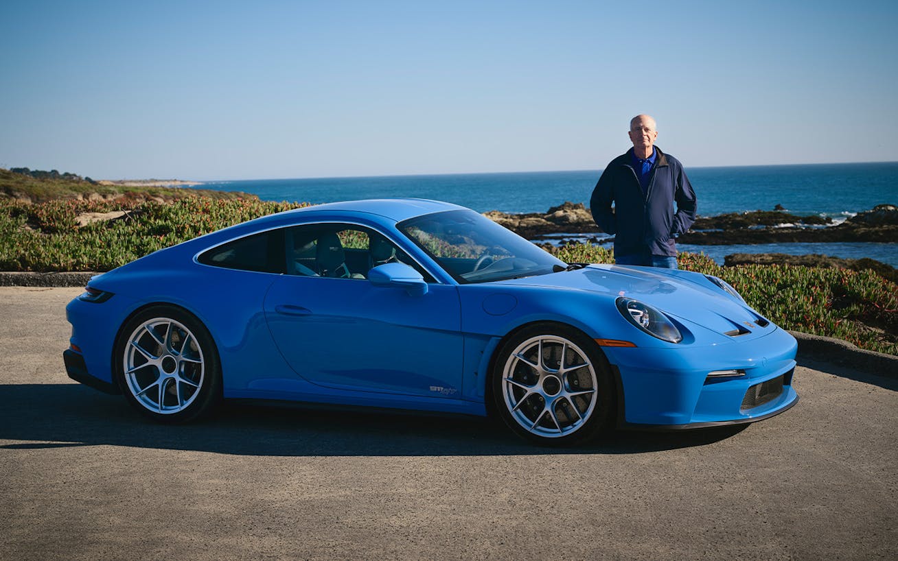 Man standing next to blue Porsche 911 S/T by the ocean