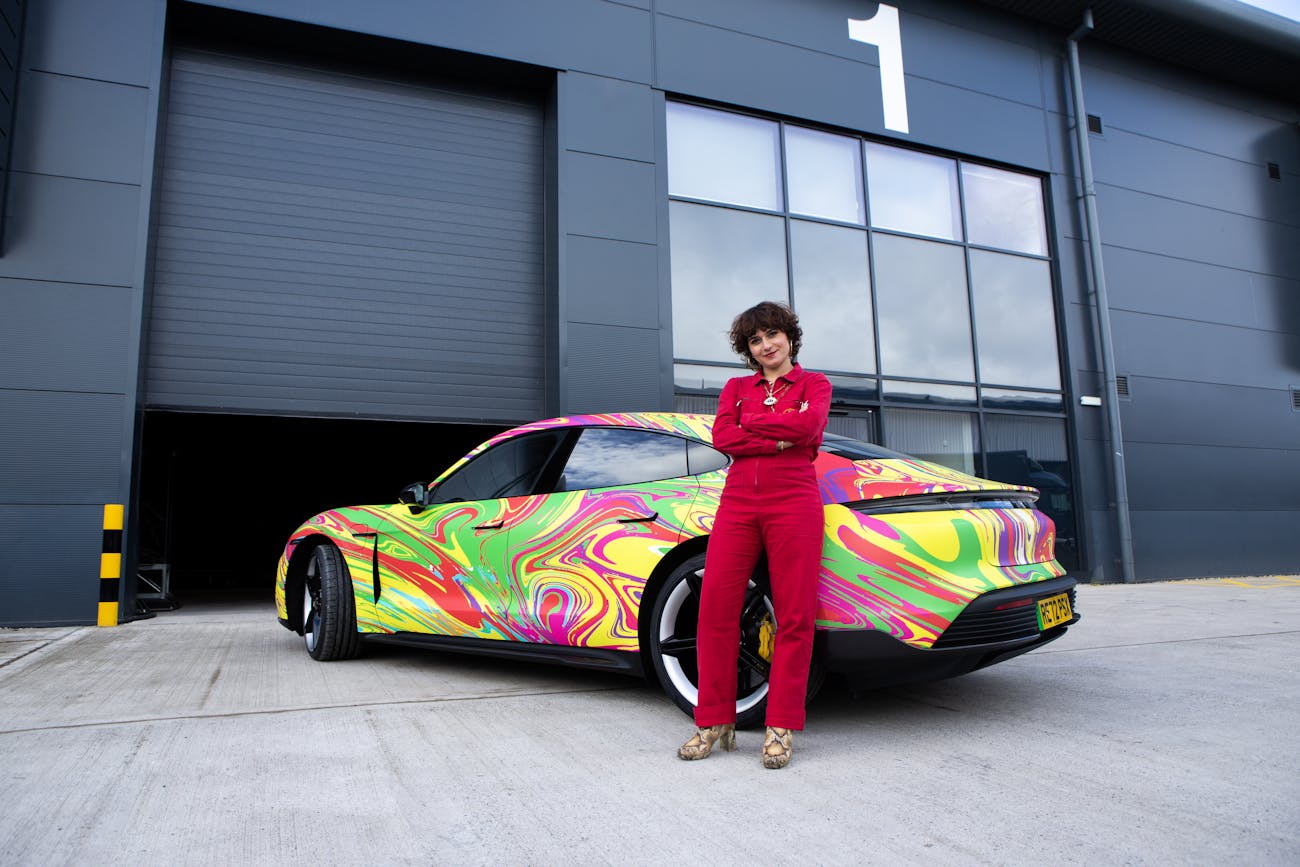 Woman in jump suit with Porsche Taycan art car