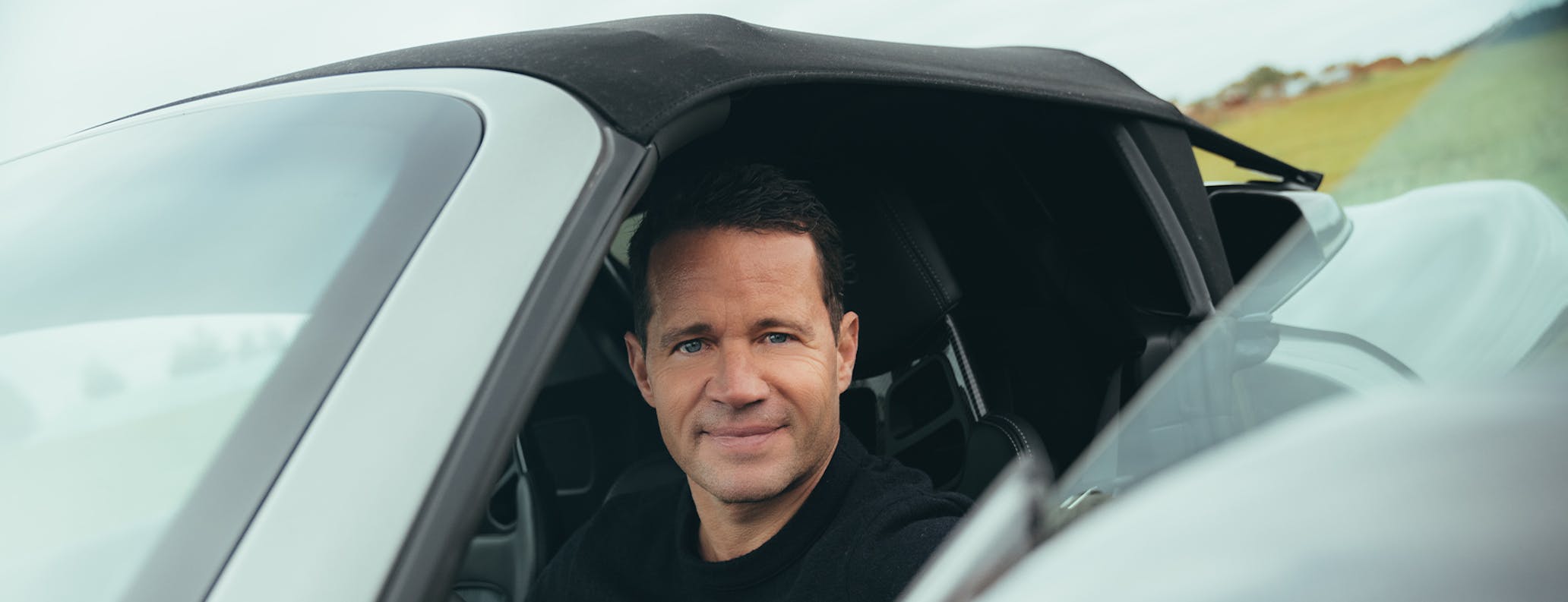 Smiling man sitting inside Porsche 718 Spyder RS