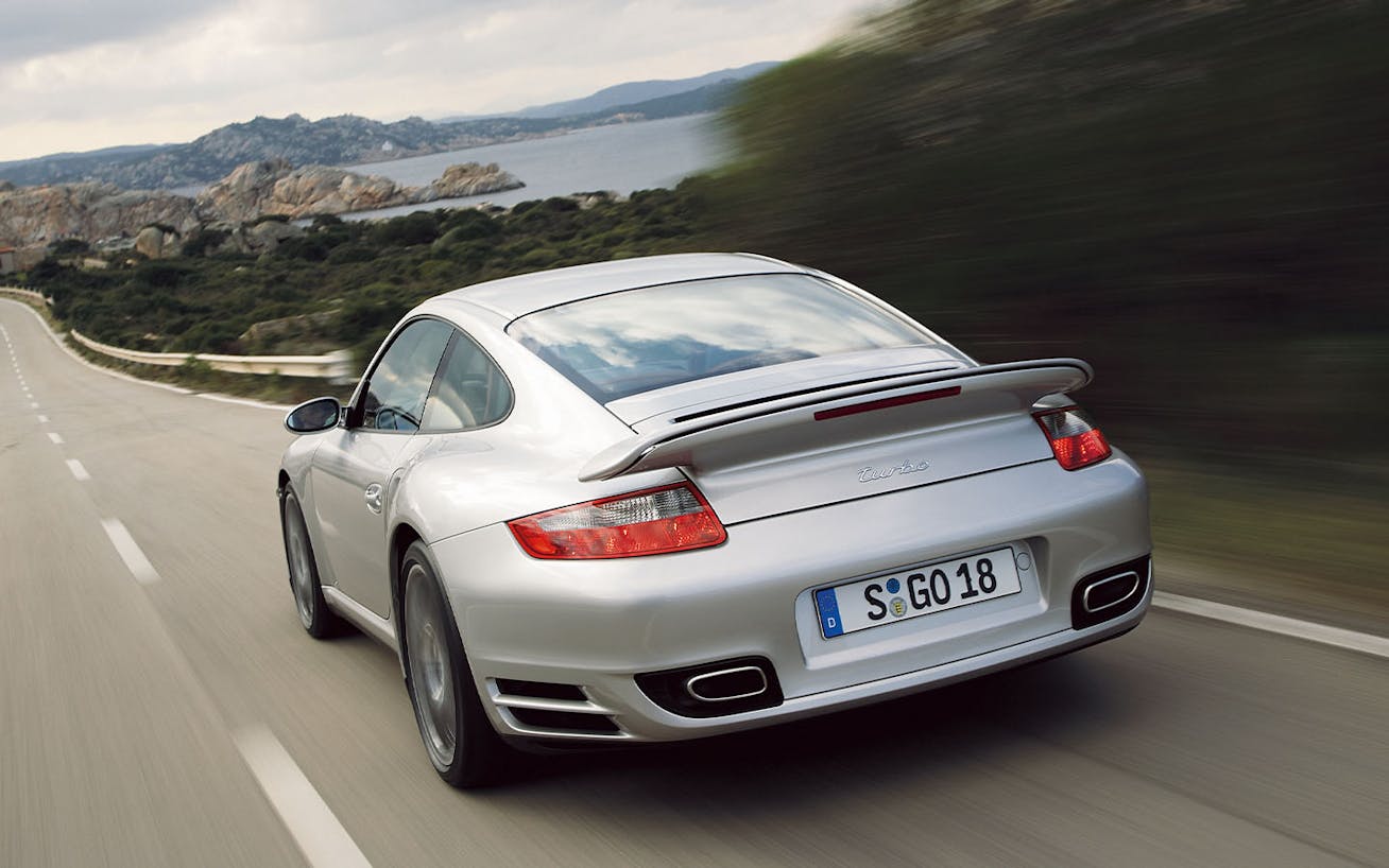 Rear view of Porsche 911 Turbo (type 997.1) driving, ocean in background