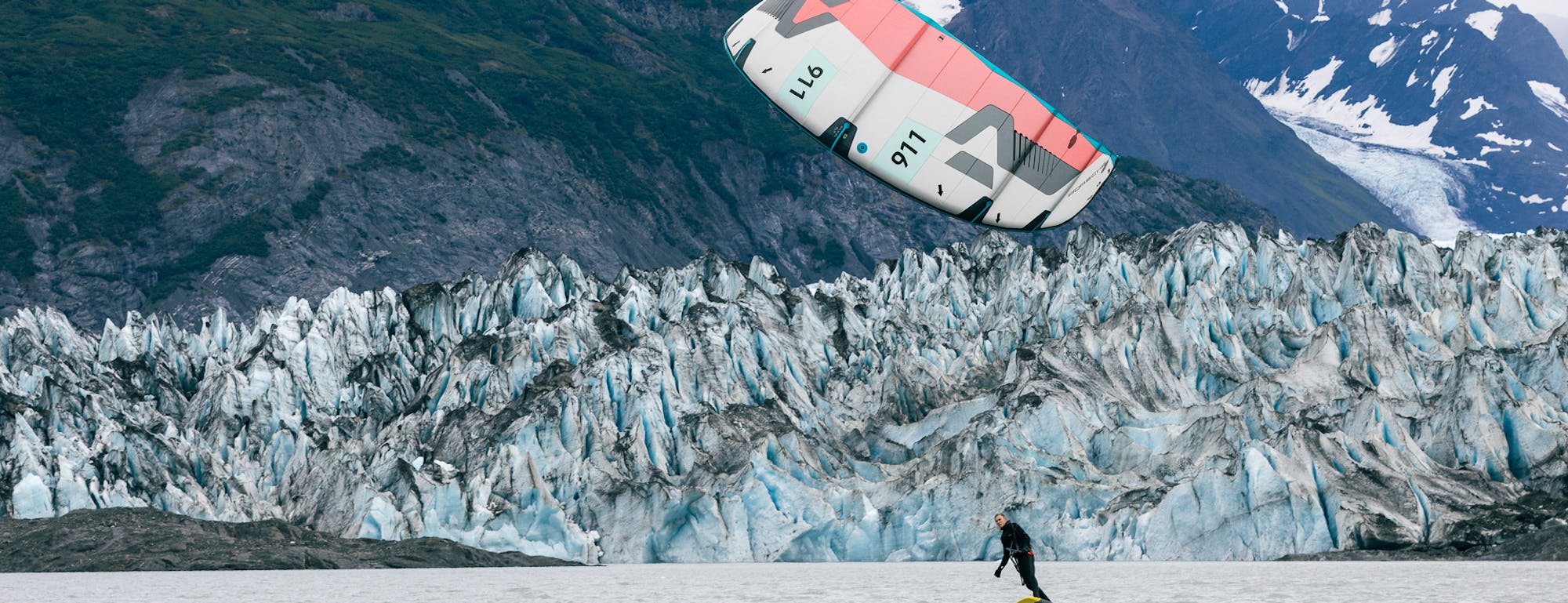 Kitesurfer on Alaskan waters, snowy mountains in background