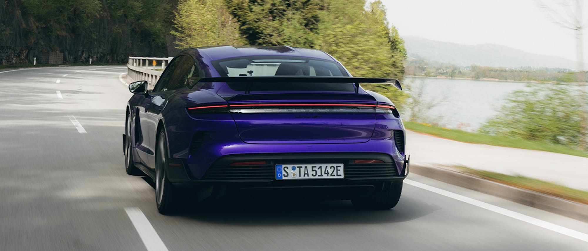 Purple Porsche Taycan Turbo GT driving on scenic lakeside road