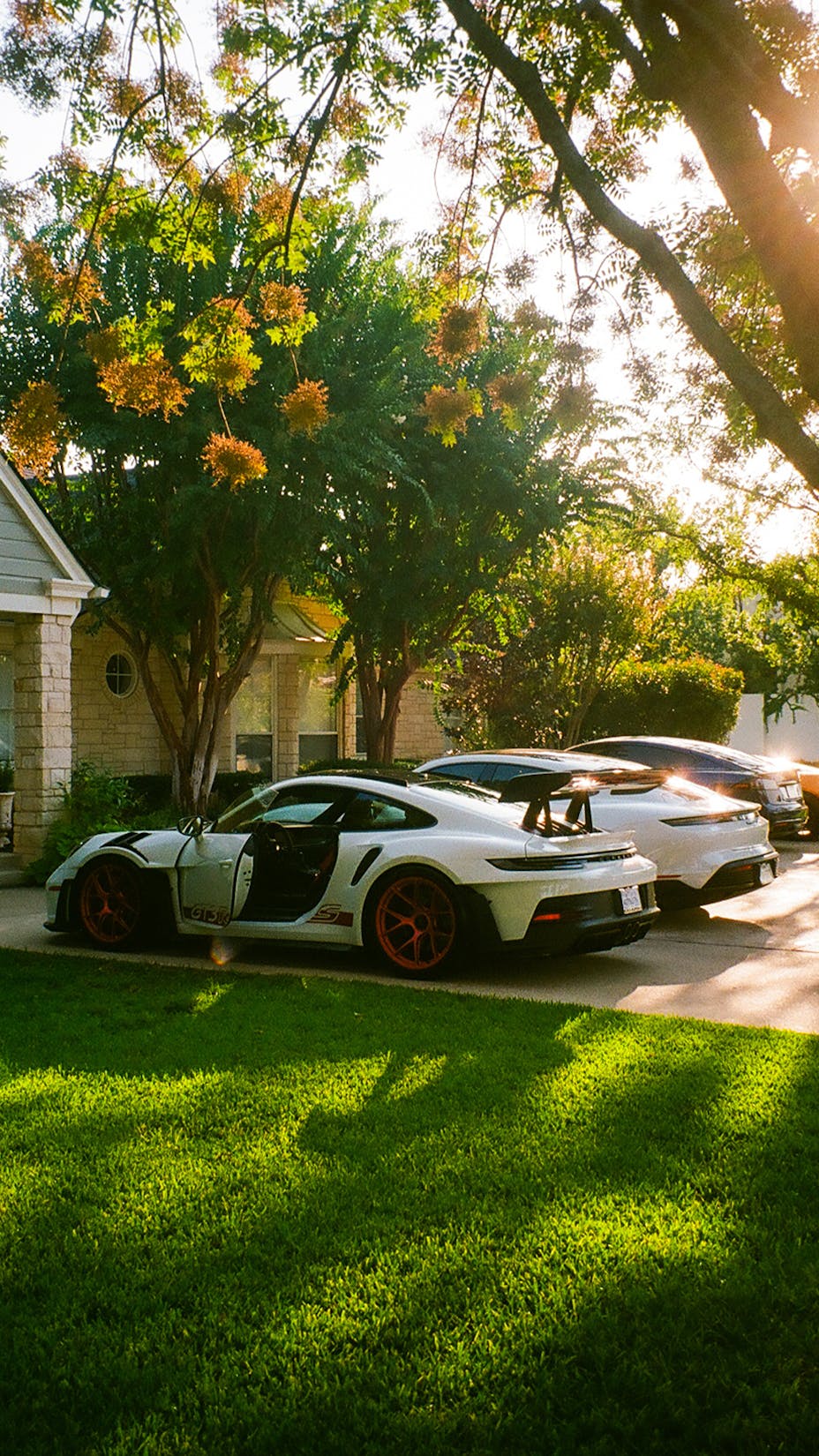 Porsche cars parked on driveway in front of house 