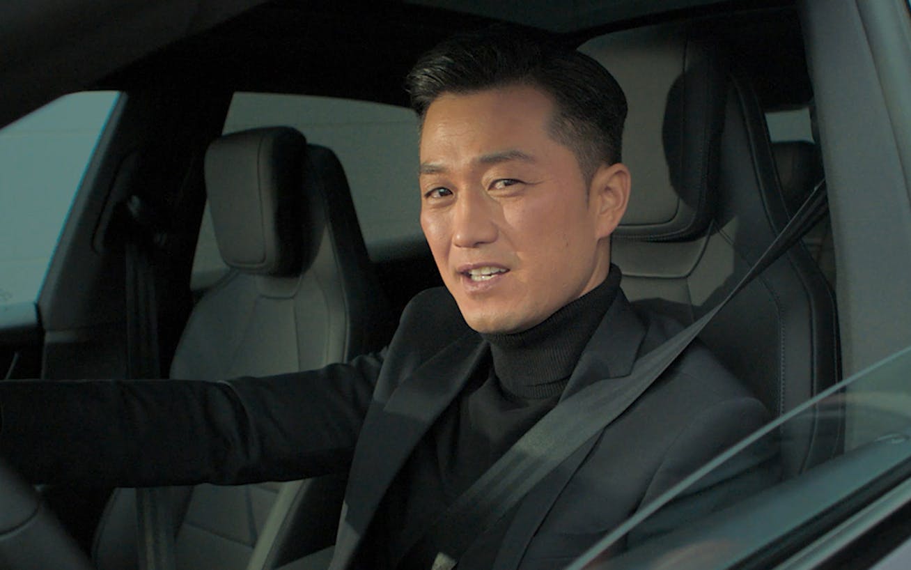 Man wearing a suit at the wheel of a Porsche Macan