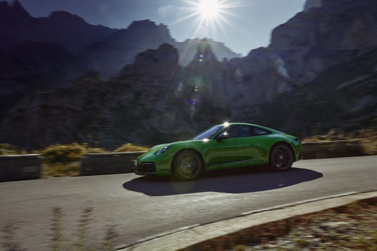 Sunlit green Porsche 911 Carrera T amid mountains