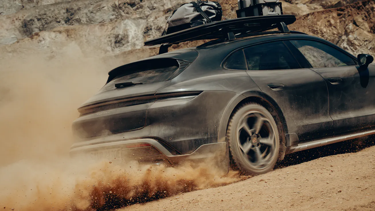 Close-up rear view of Porsche Taycan 4 Cross Turismo fitted with Adventure Accessories kicking up a cloud of dust on a gravel road 