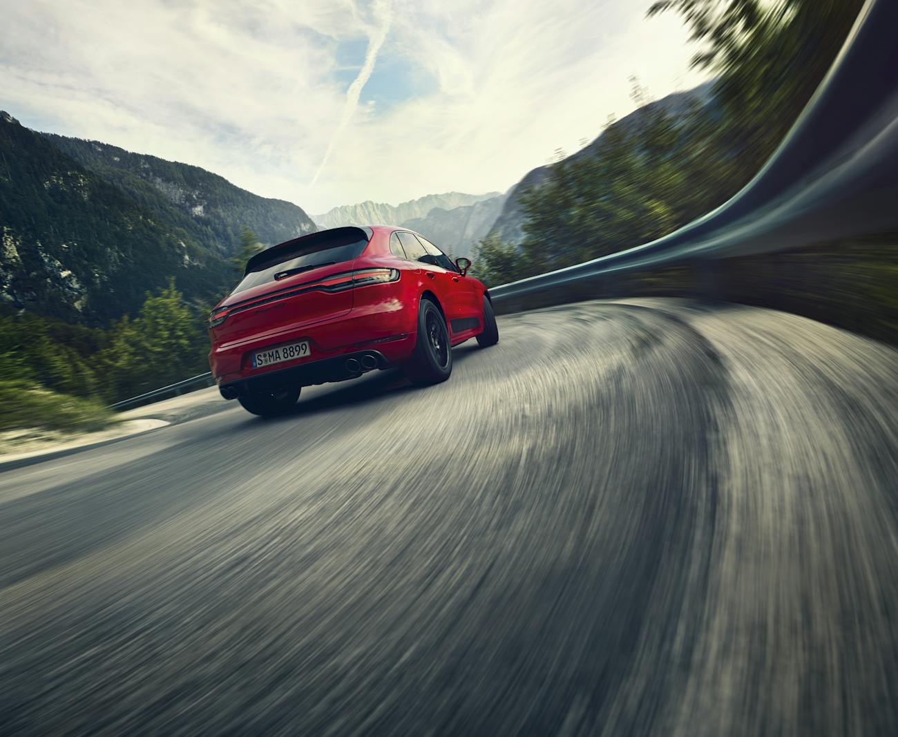 Red Porsche Macan GTS takes a curve in a road