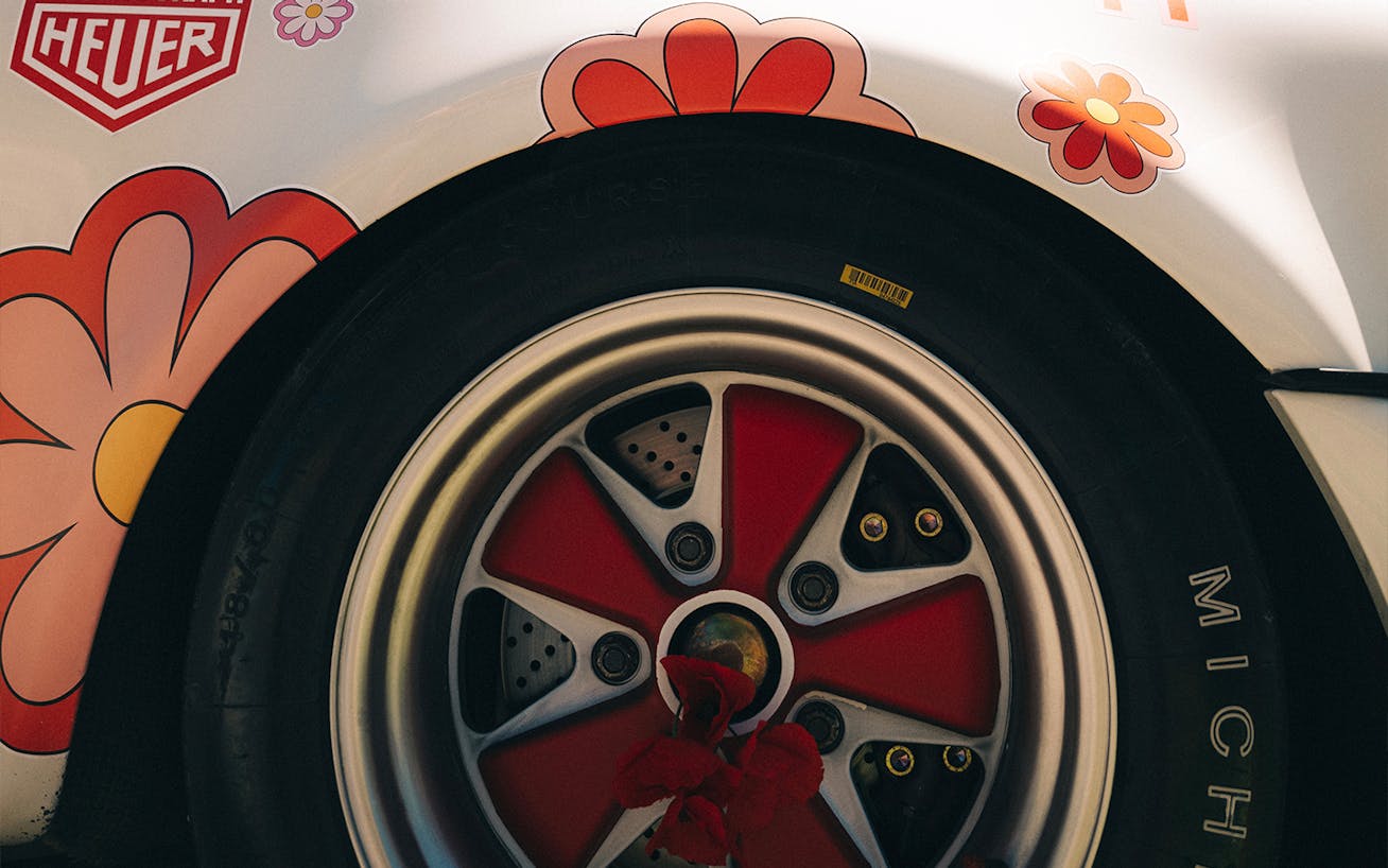 Close-up of red Porsche wheel rim surrounded by flower stickers 