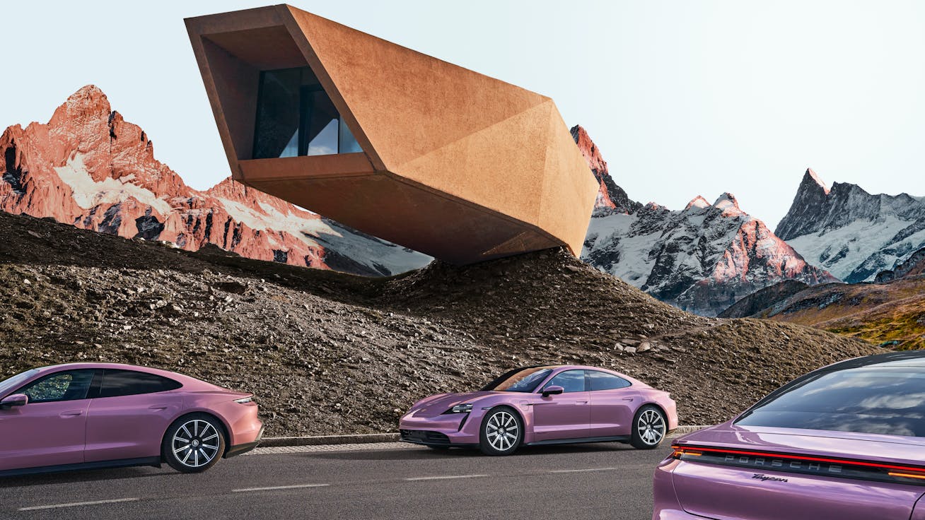 Taycan cars pass a futuristic house and mountainous backdrop