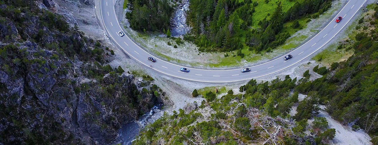 Cars drive through a sweeping bend in the mountains