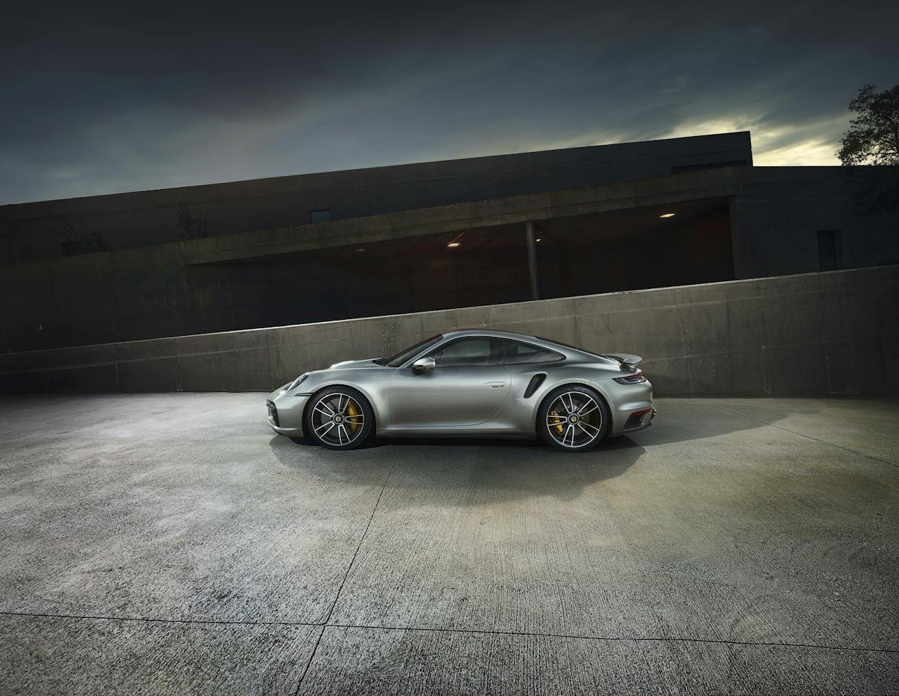 Silver Porsche 911 Turbo S (type 992) by modernist buildings