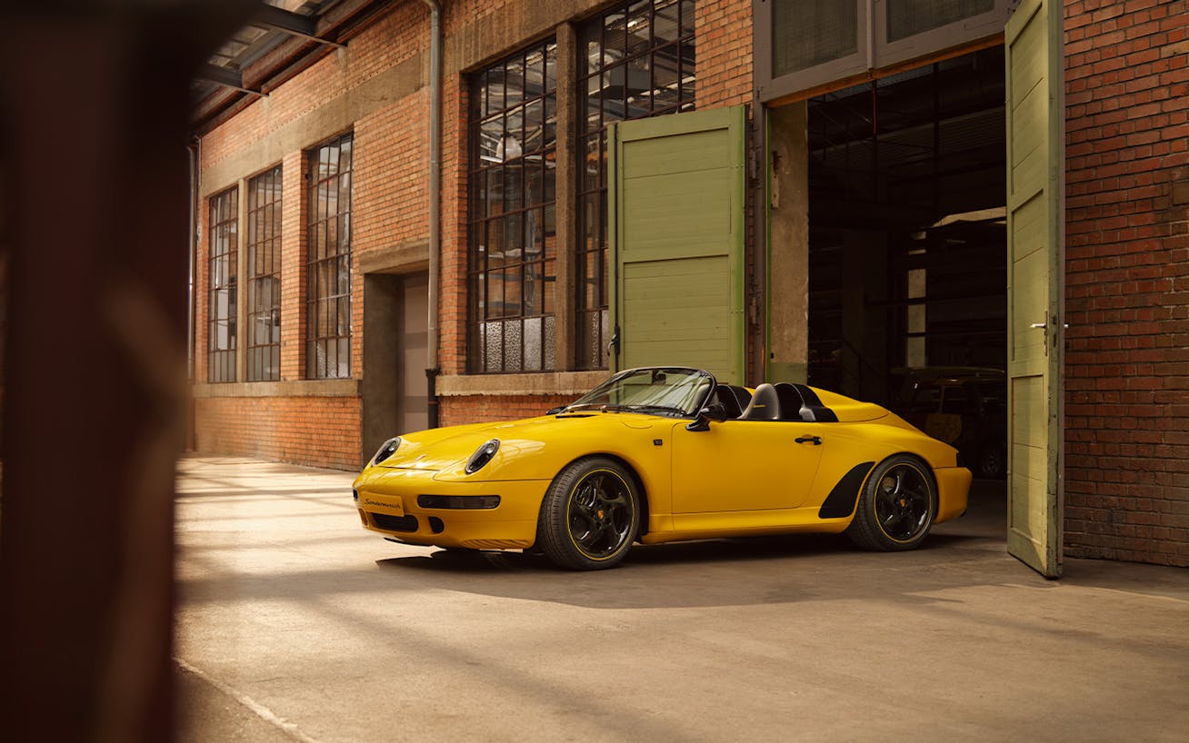 Yellow Porsche Speedster parked outside brick building