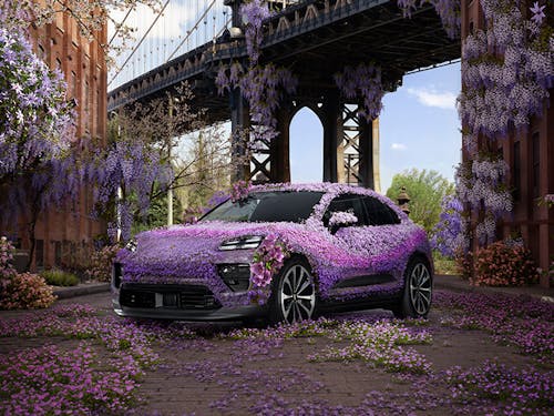 Porsche Macan covered in purple wisteria flowers, Brooklyn Bridge behind