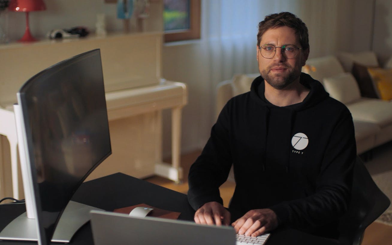 Man in black Type 7 hoodie at his computer screen