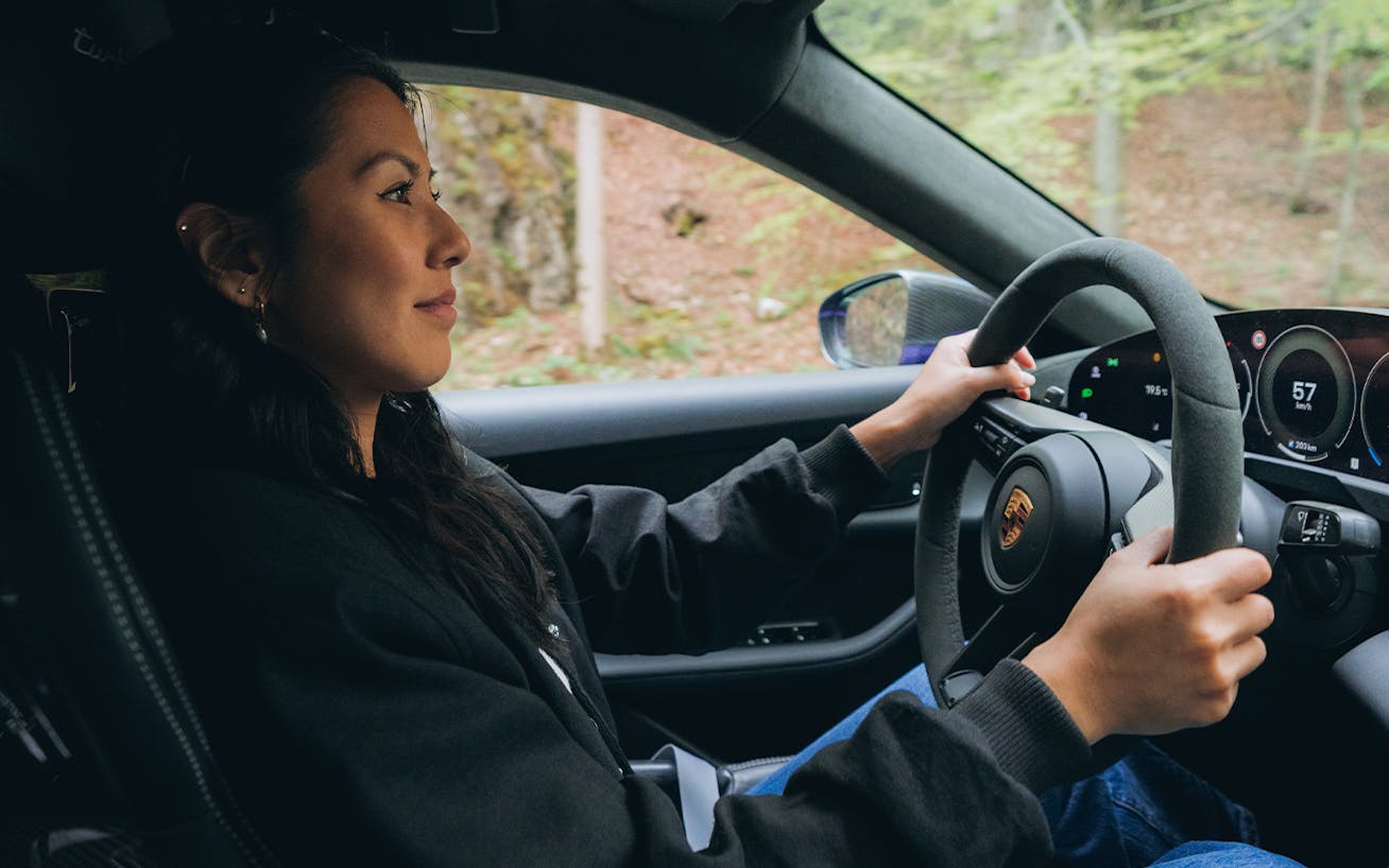 Woman driving a Taycan Turbo GT on scenic forest road