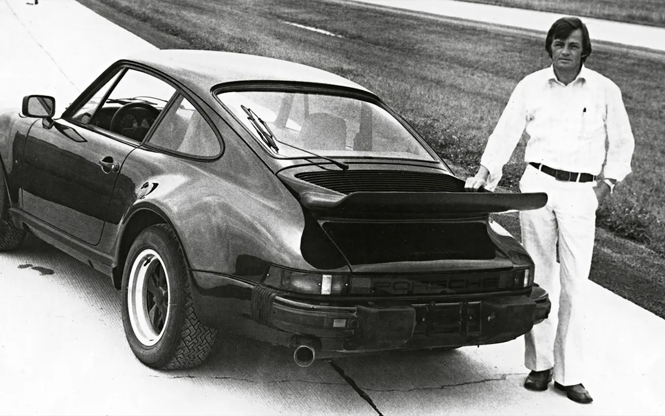 Hans Mezger with his hand placed on the whaletail rear wing of the Porsche 930 Turbo  