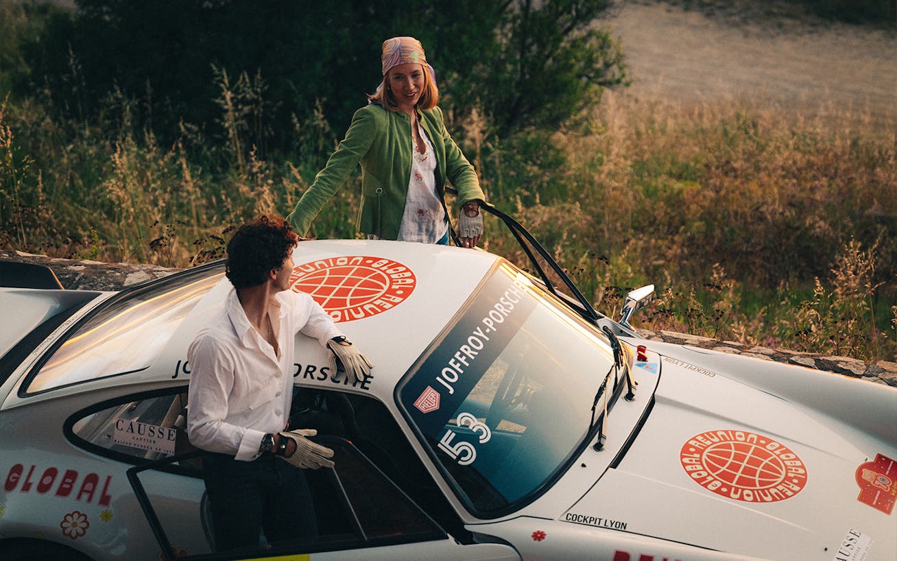 Two people standing by Porsche 3.0 RS with flower design 