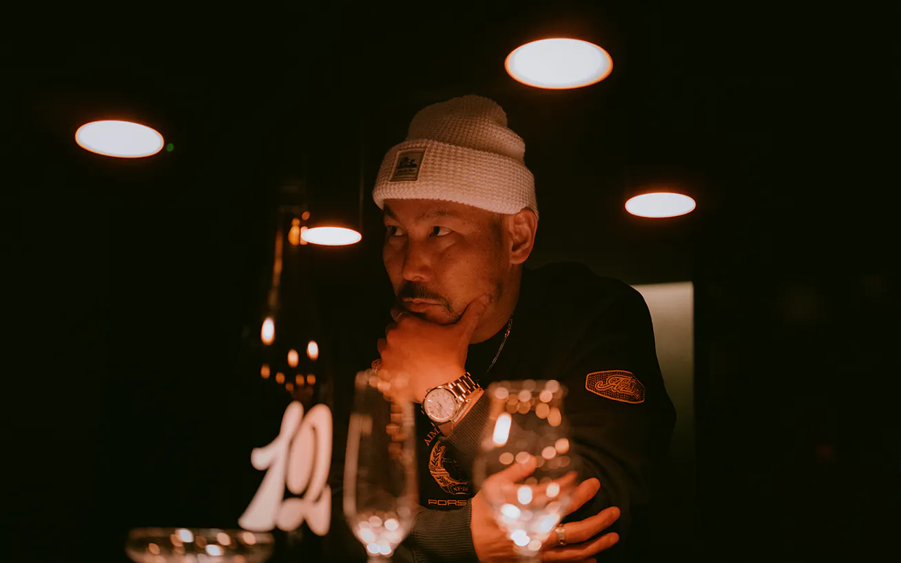 Man sitting in dimly-lit sake bar in Tokyo, surrounded by glasses