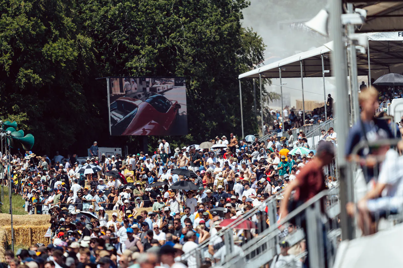 Crowds of people at the 2026 Goodwood Festival of Speed with Porsche sportscar on large TV screen