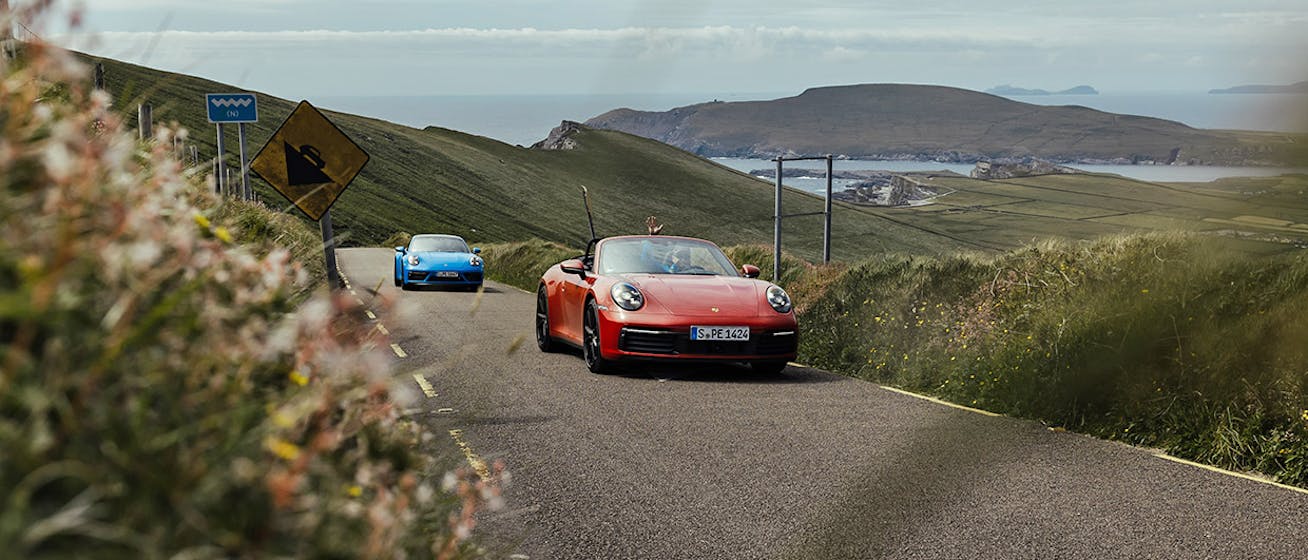 Two Porsche 911 sportscars on Irish road close to coast