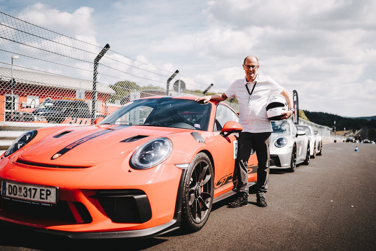 Man with racing helmet next to red Porsche 911 GT3 at Nürburgring