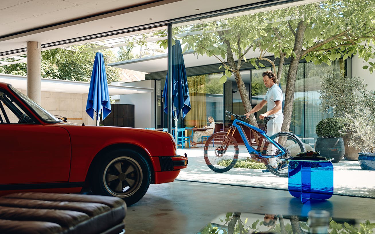 Classic red Porsche 911 and man with blue eBike in background 