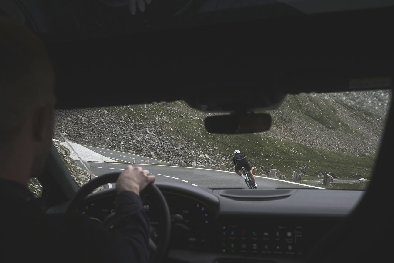 View from inside a car as cyclist corners mountain bend