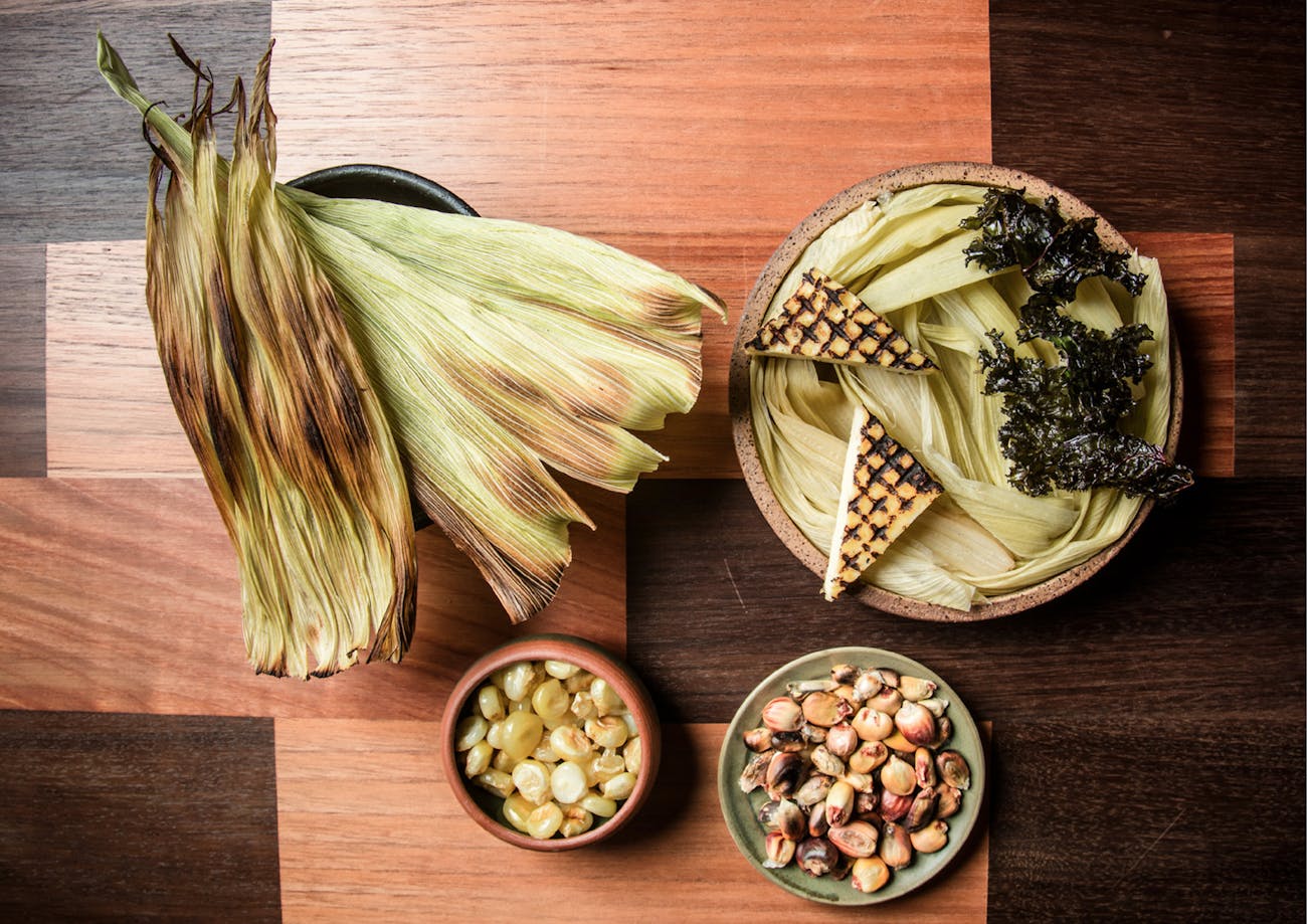 Sweetcorn kernels and corn leaves spread on a wooden table