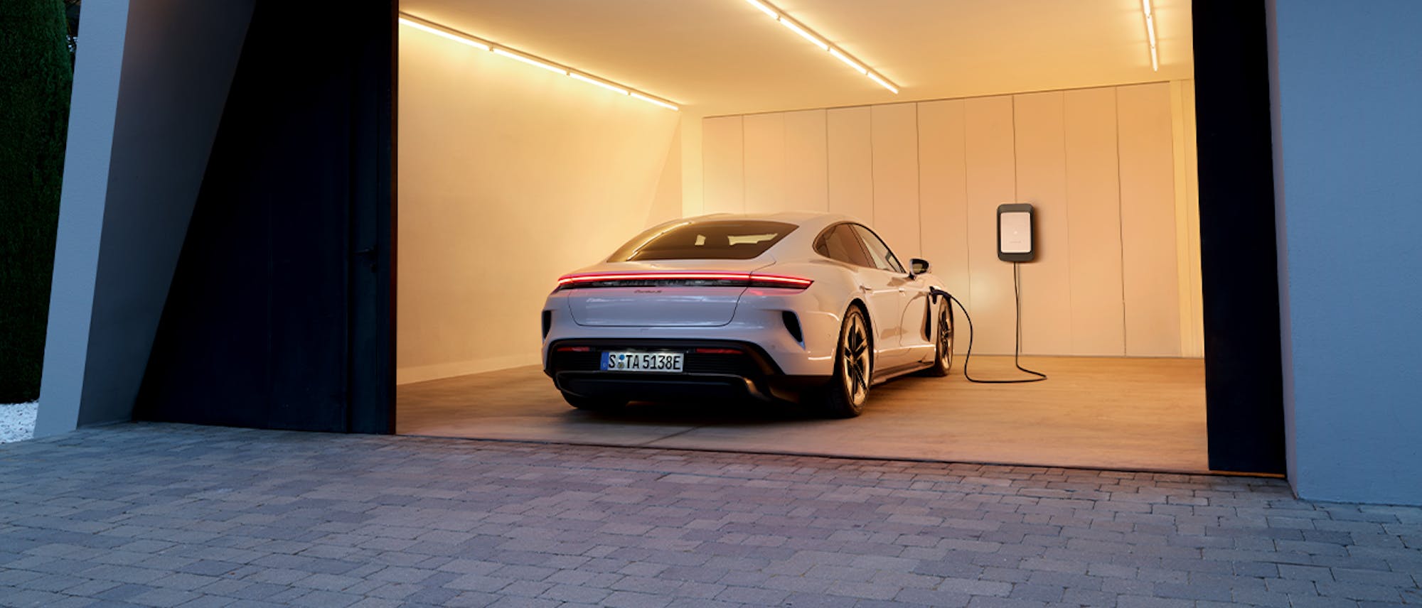White Porsche Taycan Turbo S charging in a garage