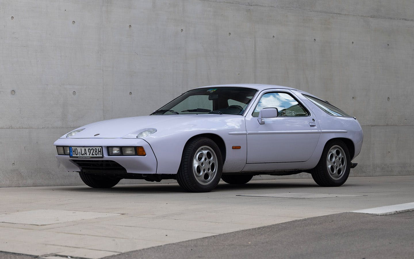 Porsche 928 in Moonstone/Flieder colour parked in front of concrete wall_gallery 4.1