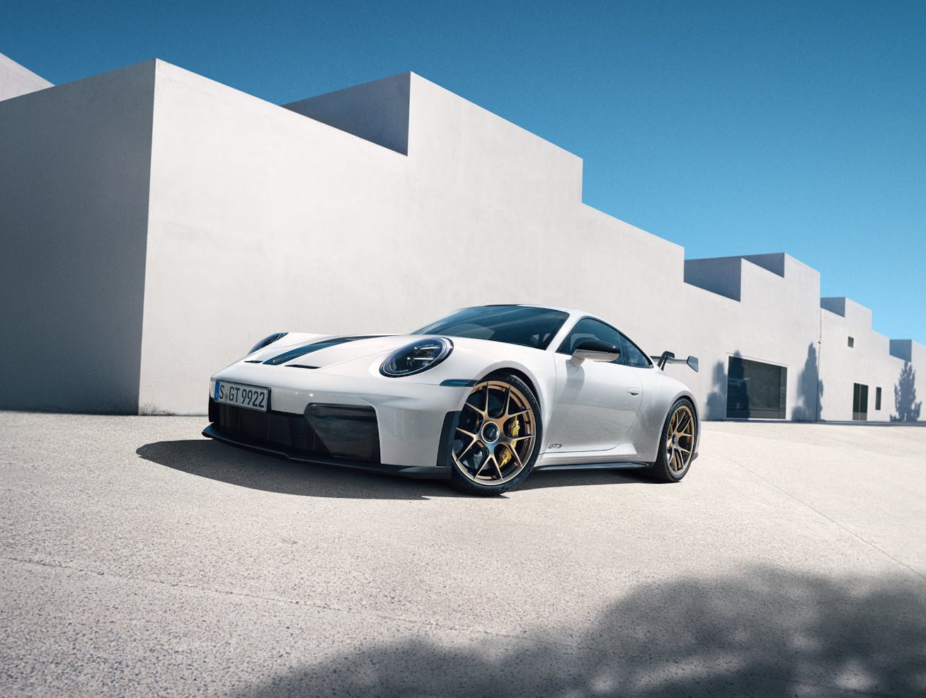 White Porsche 911 GT3 parked beside modern buildings 