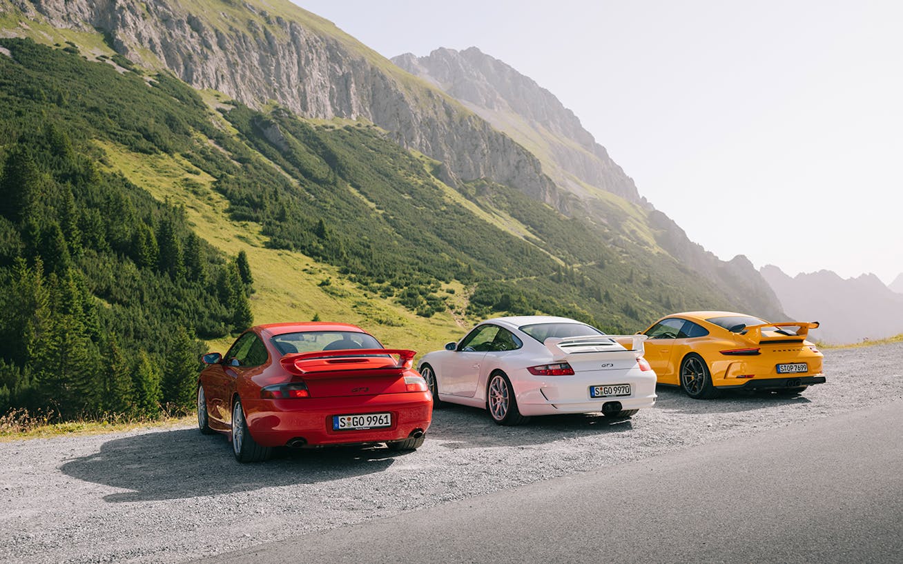 Three generations of Porsche 911 GT3 parked on mountain road