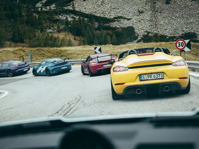 Colourful Porsche cars driving on mountain road during Gipfeltreffen