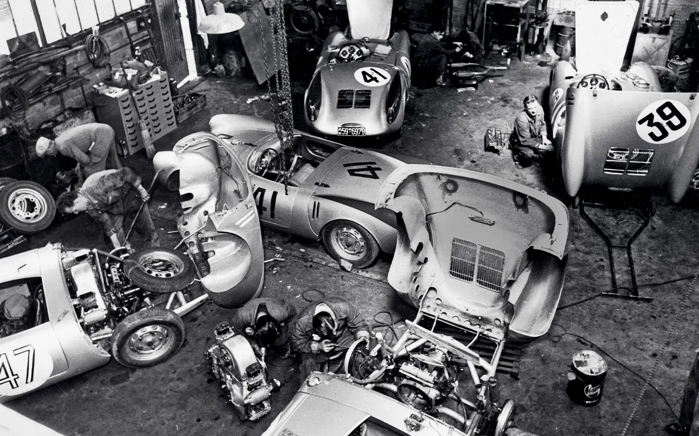 Mechanics working on Porsche 550 Spyer racecars at Teloché garage village 24 Hours of Le Mans 1955