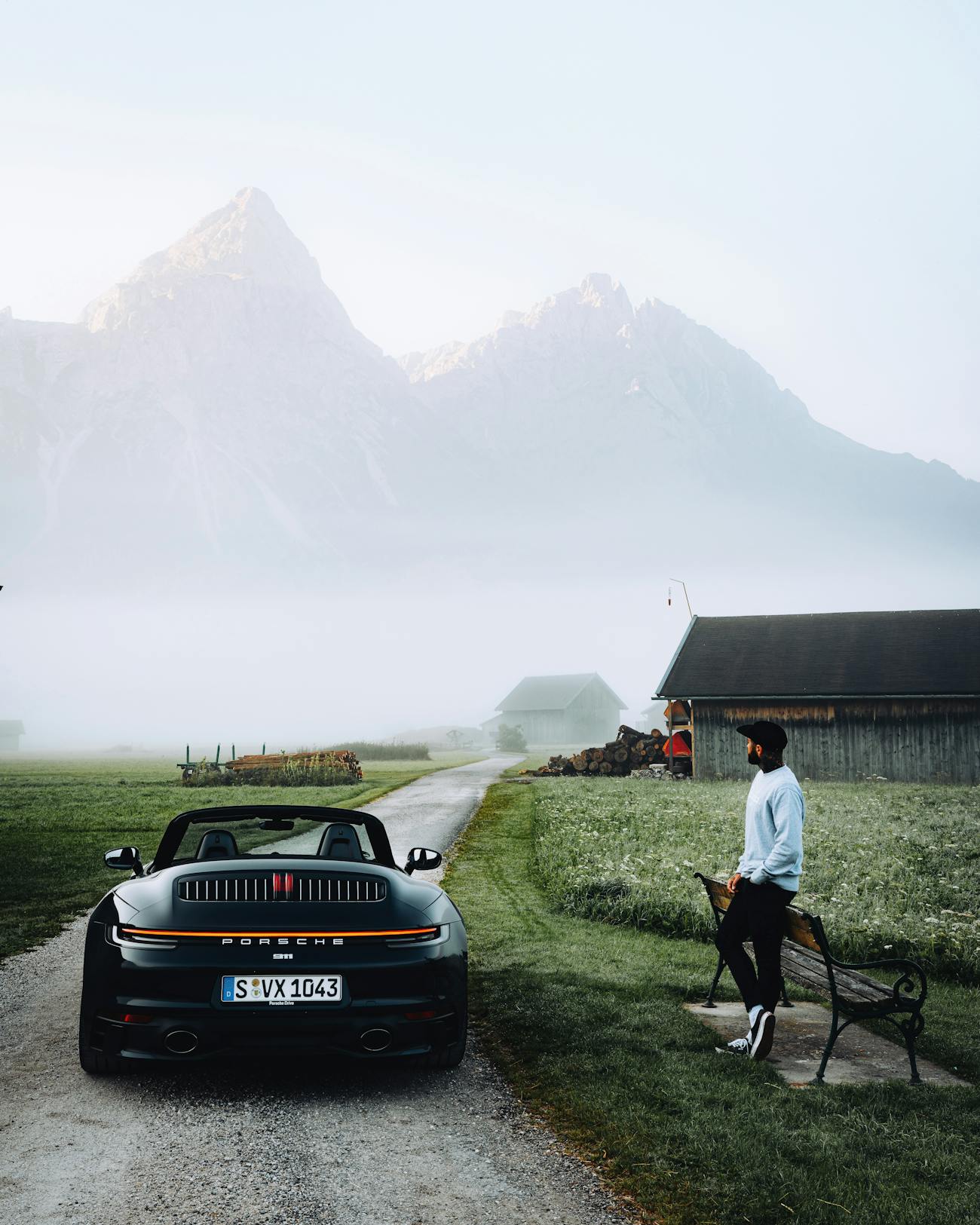Man stands next to 911 Cabriolet, misty mountain in background