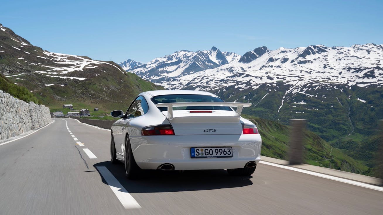 Rear view of Porsche 911 GT3 (type 996.2) driving on Alpine road