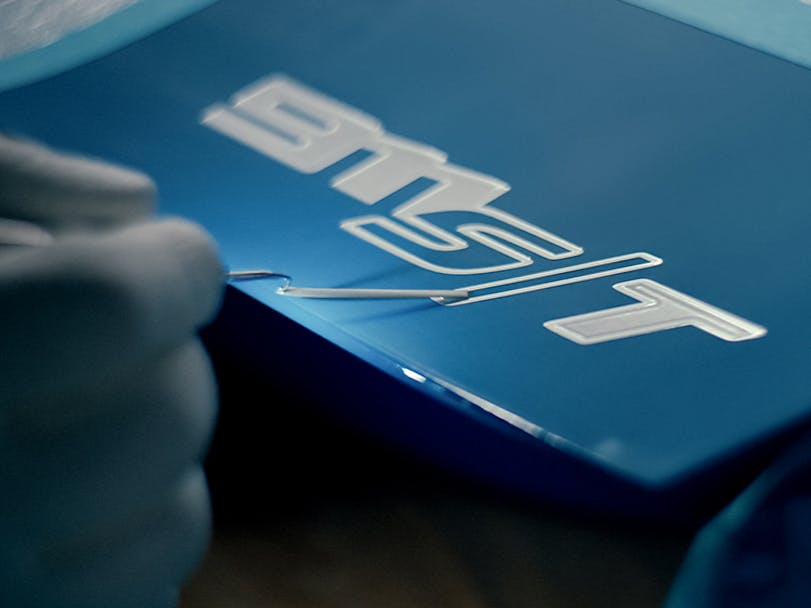 Hand applies name badge to Porsche Sonderwunsch 911 S/T sportscar