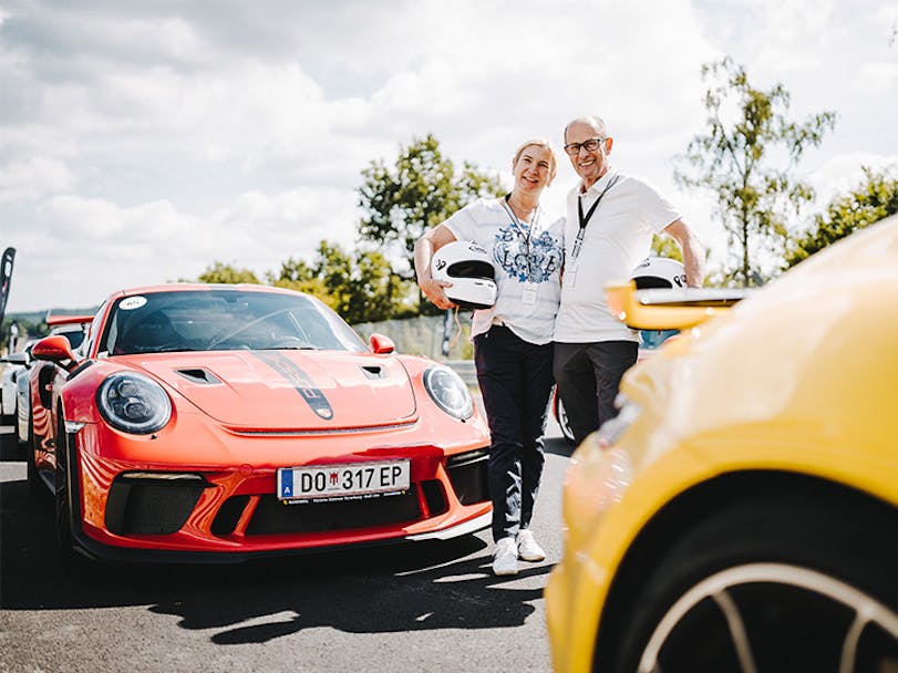 Couple stand in front of red Porsche 911 GT3 at the Porsche Track Experience at the Nürburgring [credits Photo: Porsche]