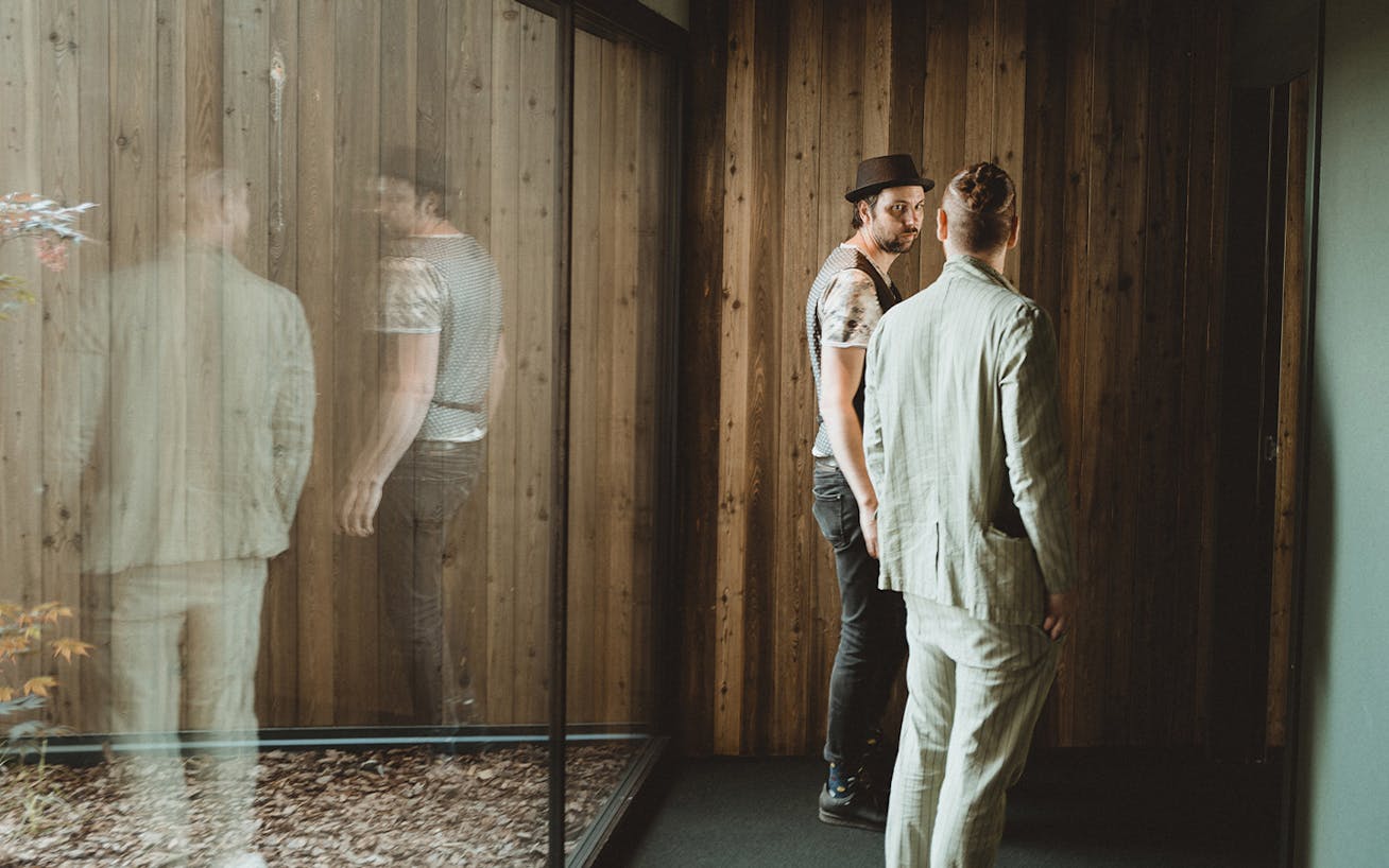 Two men with backs to window looking at each other in Swiss architect-designed house_Porsche Travel Experience