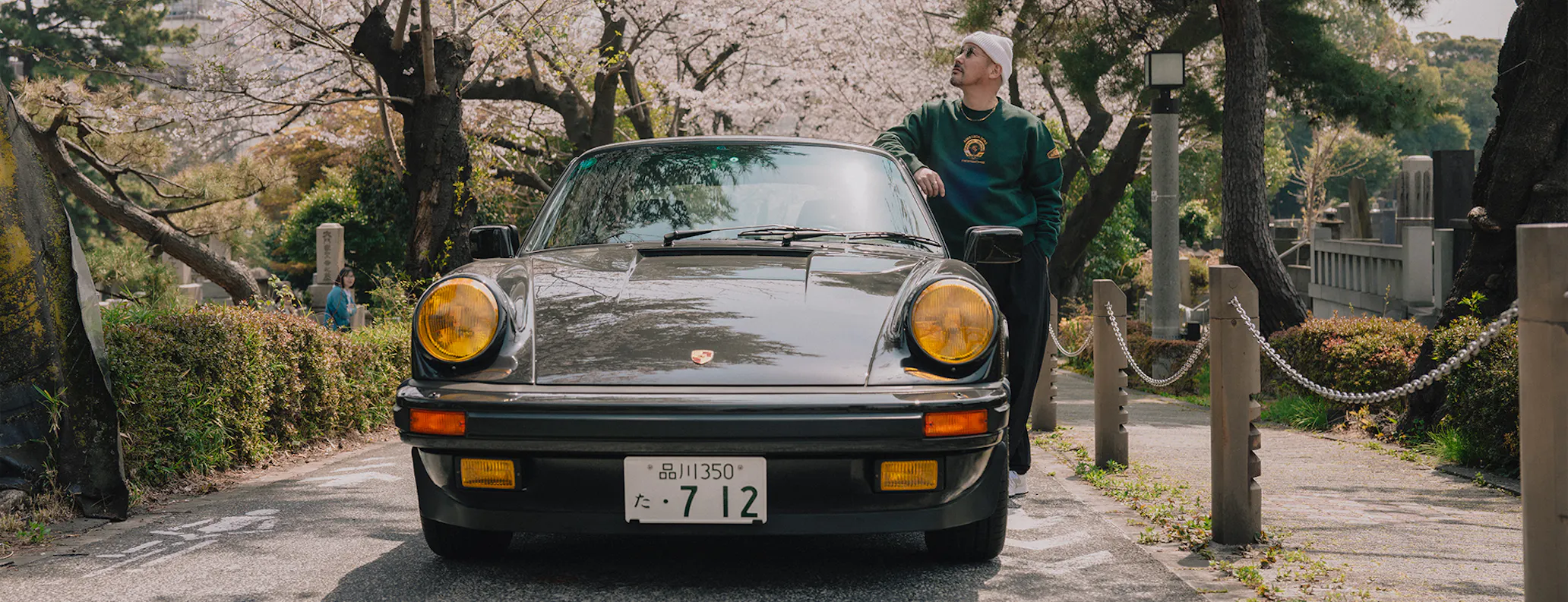 Man leaning on roof of black classic Porsche 911 Carrera S/C