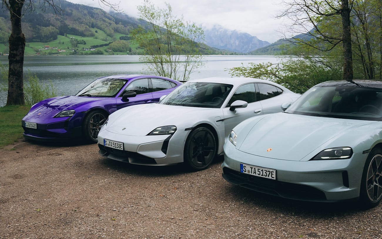 Three Porsche Taycan sportscars parked in front of lake