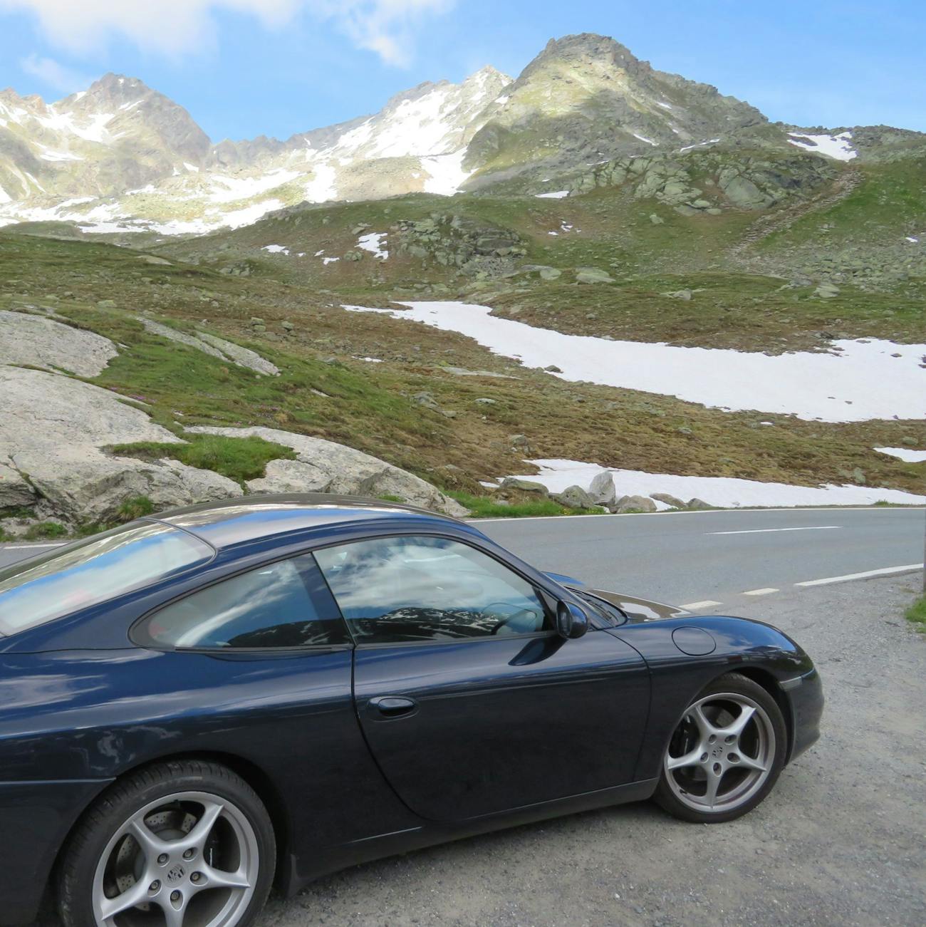 Dark blue Porsche with mountains and snowy fields behind it